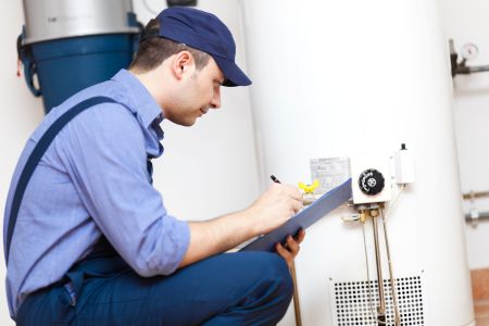 Portland plumber inspecting an aging water heater tank in a basement utility room